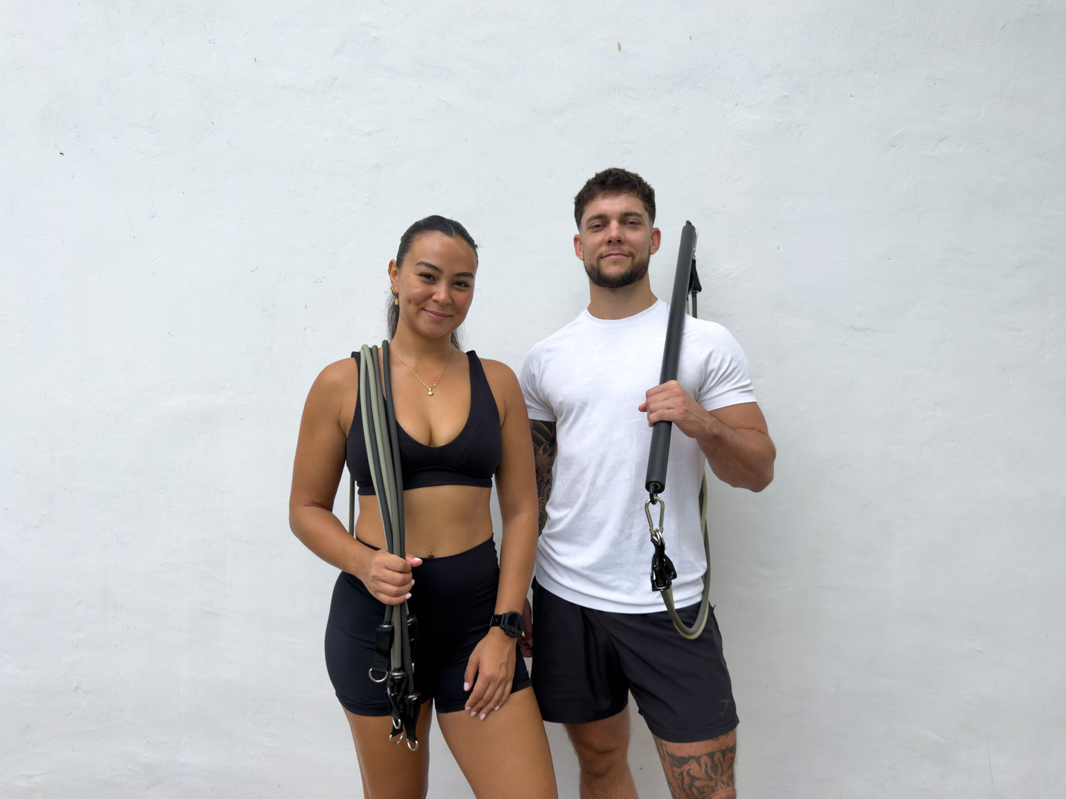 AEVO Fit founders standing together holding the two-piece bar and resistance bands